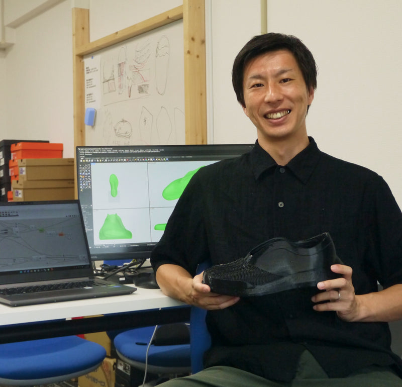 設計データを表示したモニターの前で、DIFF.3Dのシューズを手にするYuichi Shimizu
